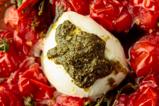 Mozzarella with pesto sauce and roasted red cherry tomatoes.