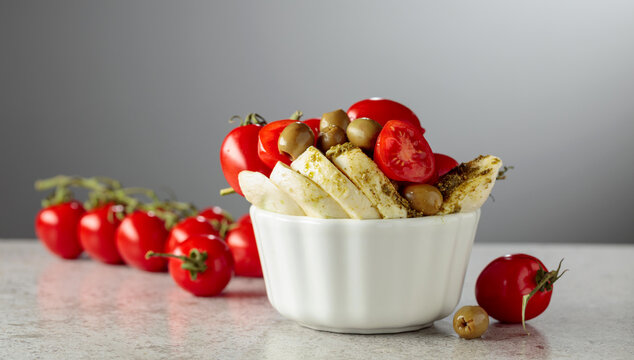 Mozzarella with pesto sauce, green olives, and red cherry tomatoes.