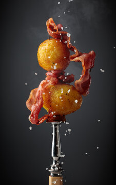 Roasted potatoes with bacon on a fork.