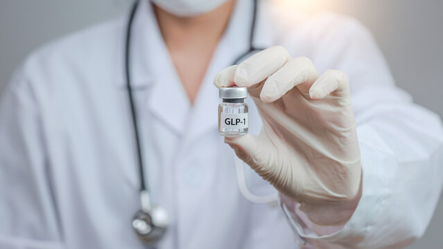 Confident doctor holds hormone vial for medical weight management treatment, offering professional clinical care with stethoscope and white glove