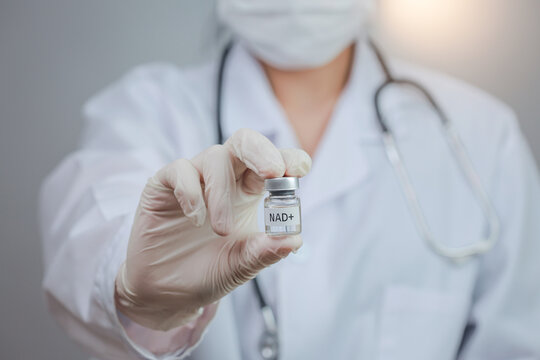 Serious doctor wearing mask glove holds medicine vial representing medical longevity concept with hopeful treatment for healthy aging
