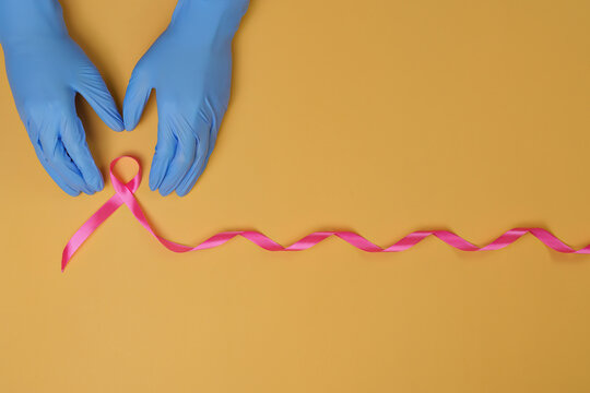Doctor hands in medical gloves forming pink ribbon for breast cancer awareness