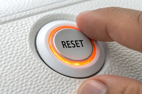 Finger pressing a circular reset button with glowing orange light technology interface electronic interaction