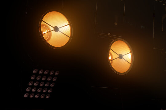 Stage lighting equipment with warm orange glow illuminating the dark performance space