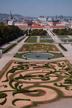 Veduta aerea e panoramica dei giardini barocchi del Palazzo del Belvedere con fontana e geometrici ricami di siepi, con lo sfondo del Belvedere Inferiore e lo skyline della citt&agrave; di Vienna, Austria.