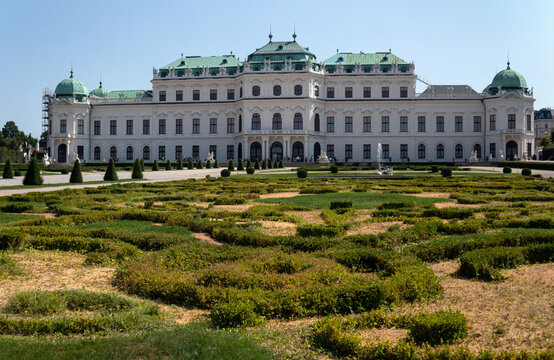 Facciata esterna del Palazzo del Belvedere Superiore con i monumentali giardini barocchi geometrici in primo piano sotto un cielo azzurro, famosa attrazione turistica e storica di Vienna, Austria.