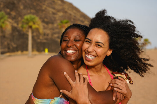 Happy multiracial girls having fun hugging each other on the beach during summer vacation - Holiday, female friendship and diversity concept