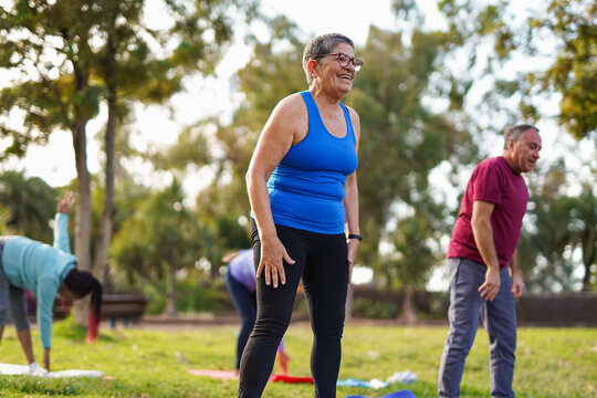Happy senior people having fun together during yoga class at city park - Fit elderly friends, healthy lifestyle and sport concept