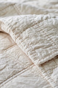 Closeup of quilted ivory bedspread showcasing soft puckered texture and hand-stitched seams under warm afternoon light