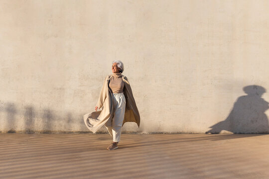 Smiling woman walking on footpath during sunny day
