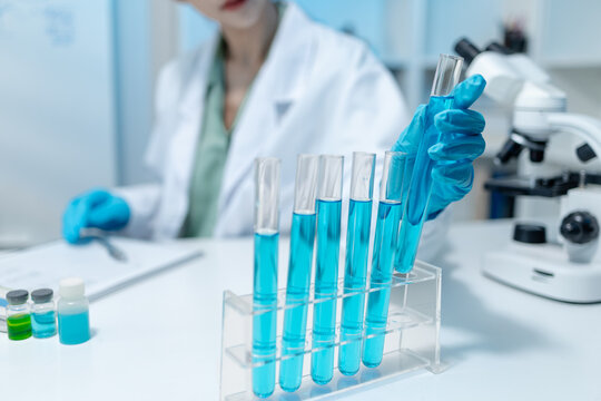 Scientists analyze liquid samples using test tubes, microscopes, and laboratory equipment, representing biotechnology, medical diagnostics, research, and healthcare innovation.