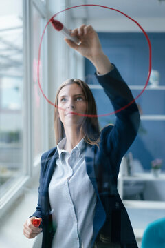 Young busnesswoman drawing a pie cahart on a glass screen