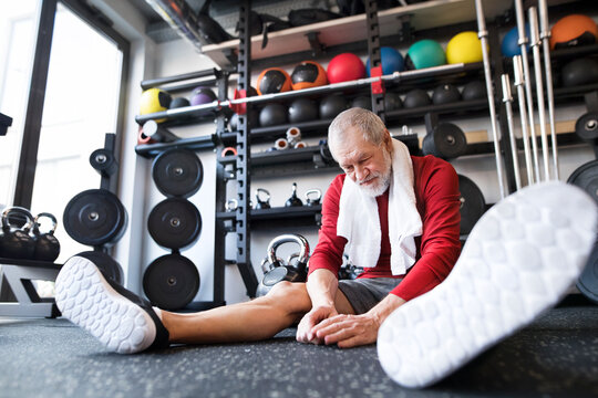 Exhausted senior man sitting on the floor after working out in gym