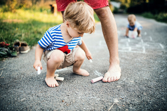 Little boy painting with chalk on asphalt