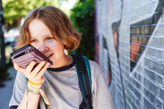 Teenage girl records a voice message on her smartphone outdoors