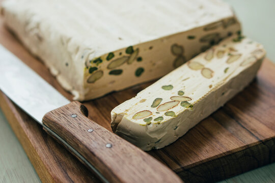 Sliced home-made turron with pistachios and almonds on wooden board