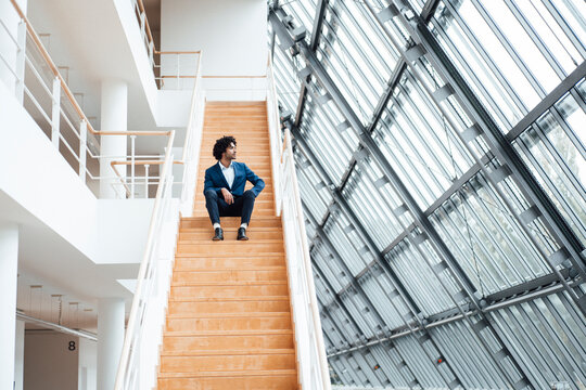 Thoughtful businessman sitting on staircase while looking away