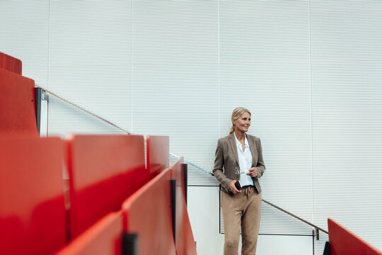Businesswoman with mobile phone standing at auditorium