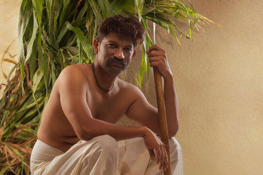Portrait of  farmer holding hoe sitting against crops