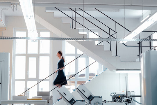 Businesswoman moving down on staircase in workshop