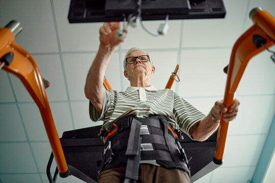 Senior man operates a rehabilitation machine in a clinic