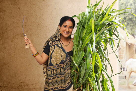 Rural woman holding bunch of crops and sickle