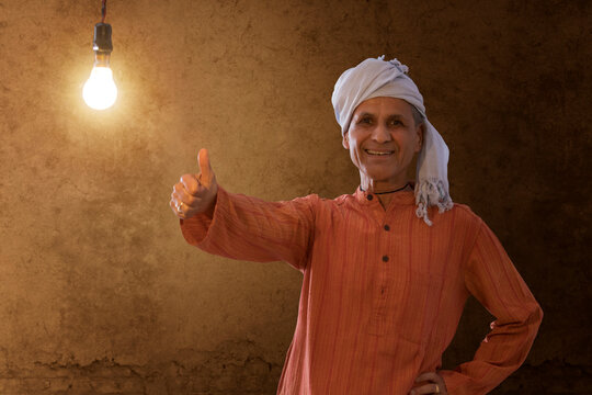 Senior rural man showing thumb up while standing against  light bulb 