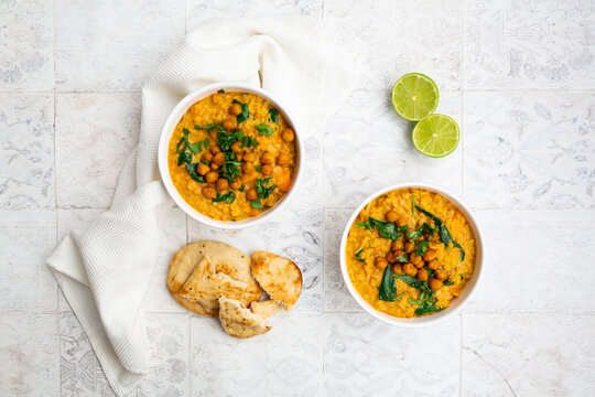 Vegan lentil curry with red lentils, sweet potatoes, spinach, roasted turmeric, chickpeas, with lime juice and coriander and naan bread