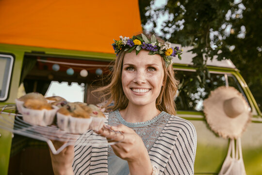 Hippie woman presenting vegan muffins in front of van