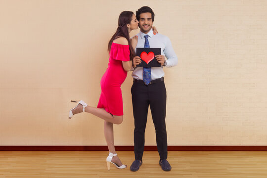 Man holding placard with a drawn heart and woman kissing