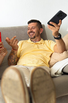 Smiling man relaxing on couch engaging in phone video call