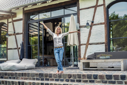 Happy owner standing in front of her country house