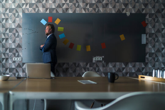 Businessman standing in front of magnet wall with a colorful headdress, made from sticky notes