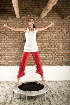 Smiling woman practices balance swing on an indoor trampoline