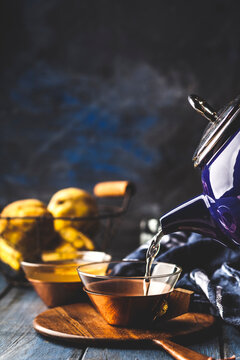 Pouring homemade hot quince infusion into tea cup