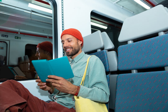Smiling man reads an ebook during his metro journey in Barcelona