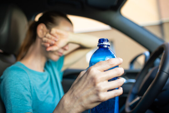 Woman Feeling Heat Exhaustion In Car While Holding Drinking Water During Summer Heatwave And Dehydration Concept
