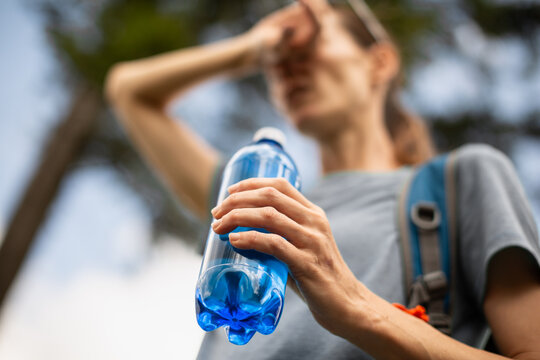 Exhausted Female Hiker Holding Water Bottle Outdoors During Summer Adventure With Heat And Dehydration Concept
