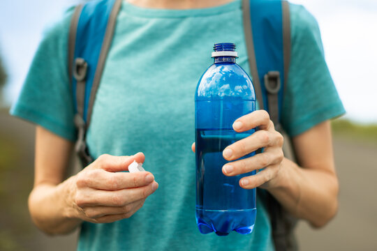 Close Up Of Woman Holding Drinking Water During Summer Heat While Staying Hydrated On Outdoor Hike
