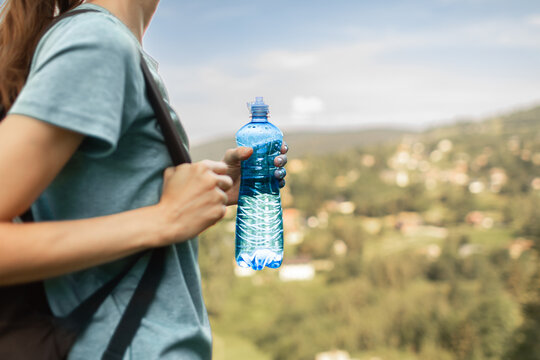 Close Up of Woman Holding Water Bottle During Summer Hike to Stay Hydrated
