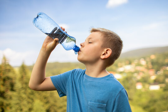 Happy Young Boy Drinking Water Outdoors On Sunny Summer Day Staying Hydrated During Healthy Active Lifestyle