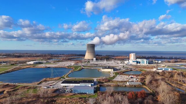 Davis-Besse nuclear power plant cooling tower producing steam in Oak Harbor, Ohio, wide drone shot