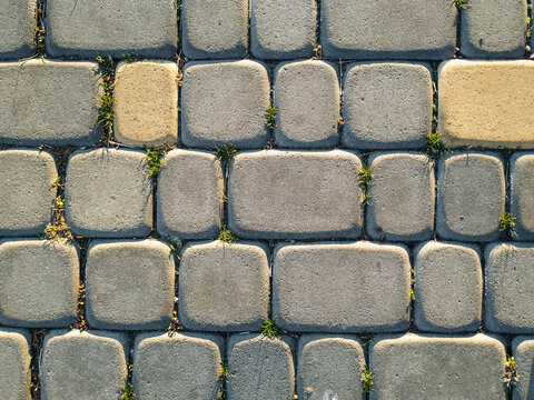 The texture of dark gray granite paving stones in the light of the setting sun. Natural block stone background. View from above.