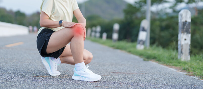 Young adult female runner with knee pain from ACL injury or patellofemoral syndrome. woman having joint ache, ligament tear or patellar tendinitis during running. Sports medical and healthcare concept