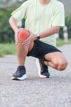 Young adult male runner with knee pain from ACL injury or patellofemoral syndrome. Man having joint ache, ligament tear or patellar tendinitis during running. Sports medical and healthcare concept