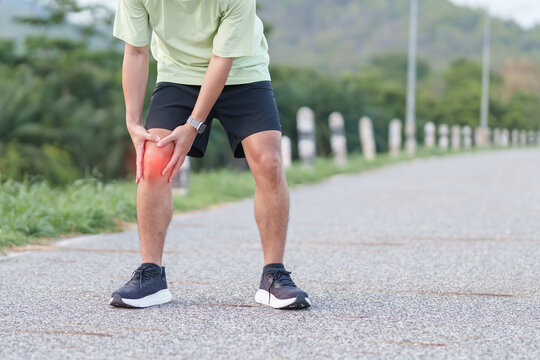Young adult male runner with knee pain from ACL injury or patellofemoral syndrome. Man having joint ache, ligament tear or patellar tendinitis during running. Sports medical and healthcare concept