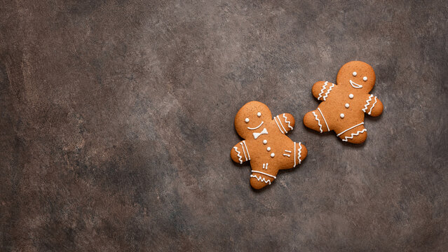 Two gingerbread men on a dark rustic background flat lay, top view. Christmas symbol