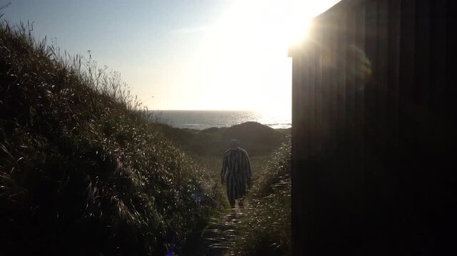 Hirtshals, Denmark A man walks in the sandy and grassy North Sea dunes at sunset. 