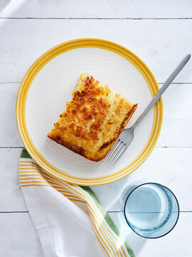 Baked cheesy casserole slice on a plate with fork, cozy home dining experience, family meal concept