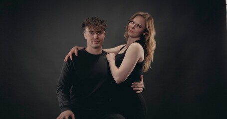 Obraz premium Young couple standing against a black background, showing connection and affection